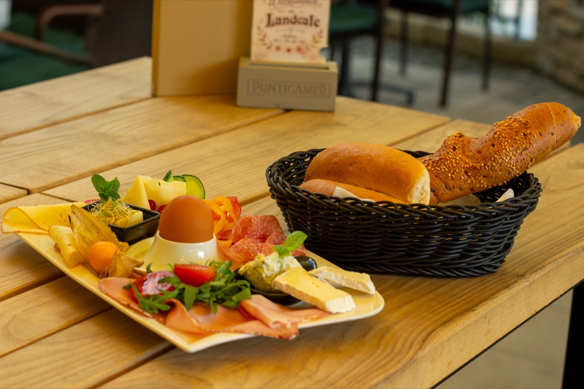 Frühstücksjause mit Schinken, Käse, weichem Ei und einem Korb frischer Semmeln
