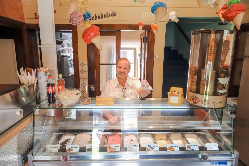 Herwig Hofer reicht eine Eiswaffel über die Eisvitrine