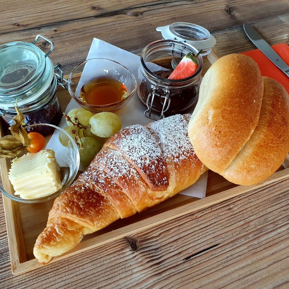 Frühstücksbrett mit Croissant, Semmeln, Butter, Honig und Marmelade